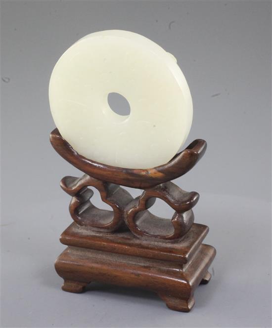 A Chinese white jade bi disc, diameter 4.6cm, wood stand